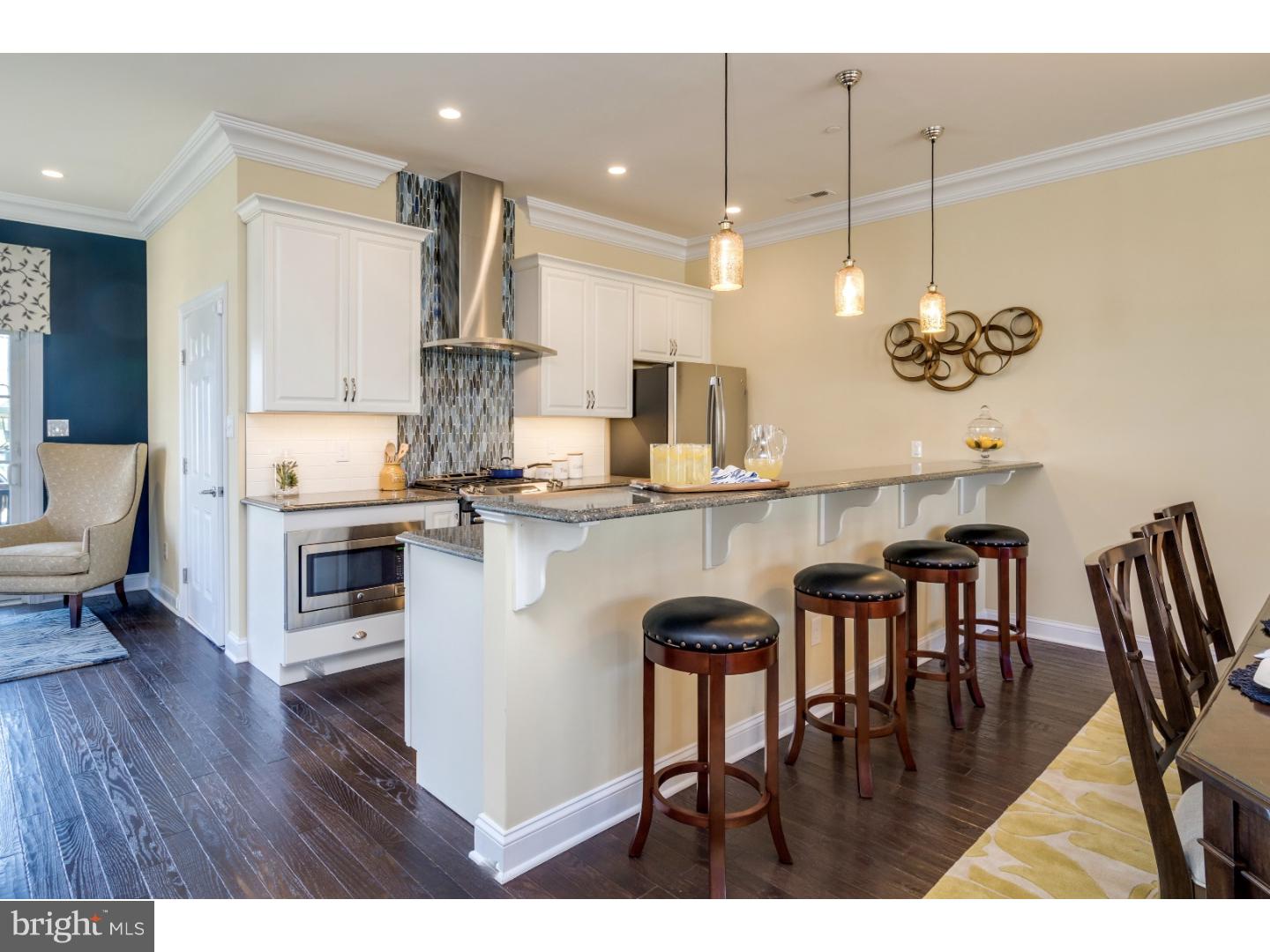 a kitchen with kitchen island stainless steel appliances a dining table chairs sink and stove