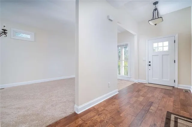 a view of an empty room with window and wooden floor