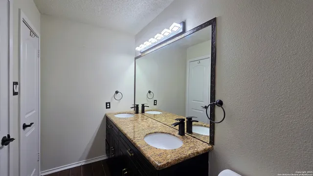 a bathroom with a granite countertop sink and a mirror