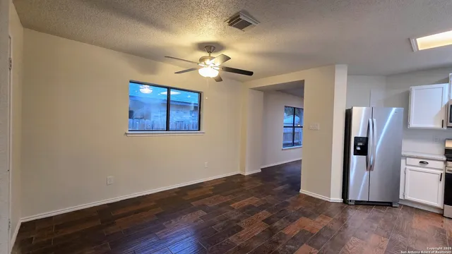 a view of a kitchen with wooden floor a ceiling fan and a refrigerator