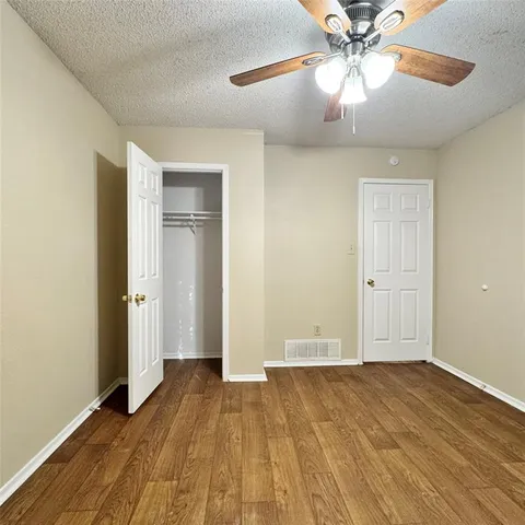 a view of a room with wooden floor and ceiling fan