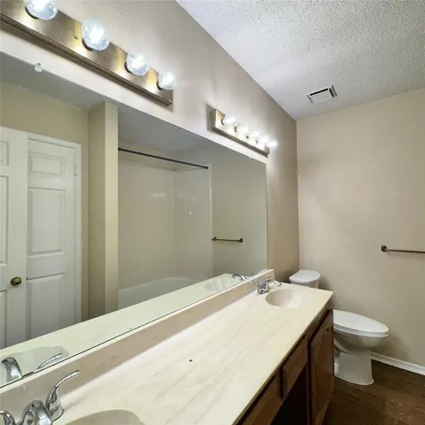 a bathroom with a granite countertop sink toilet and a mirror