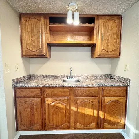 a kitchen with granite countertop a sink a stove and wooden cabinets