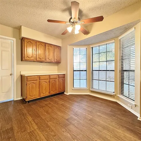 a view of a kitchen with an empty room and wooden floor