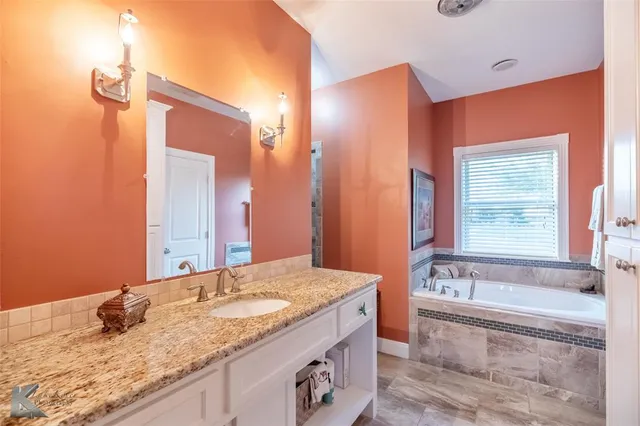 a bathroom with a granite countertop sink and a bathtub