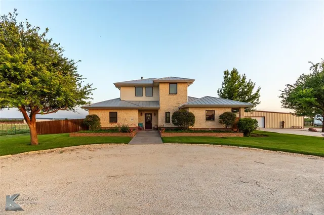 a front view of a house with a yard and trees