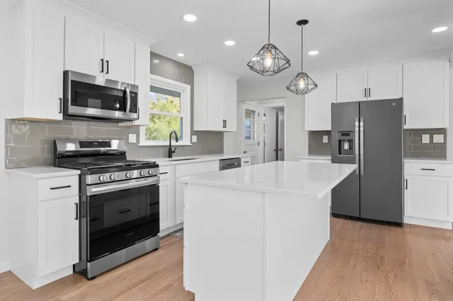 a kitchen with stainless steel appliances a stove a microwave and white cabinets
