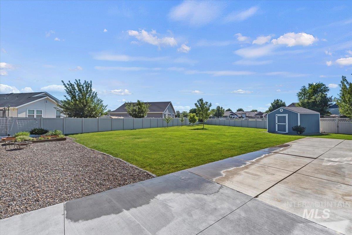 12310 West Hidden Point Drive Star, ID 83669 - Photo 38 of 48 Expansive backyard featuring a large concrete patio, a dedicated gravel area, a manicured lawn, and a detached storage shed