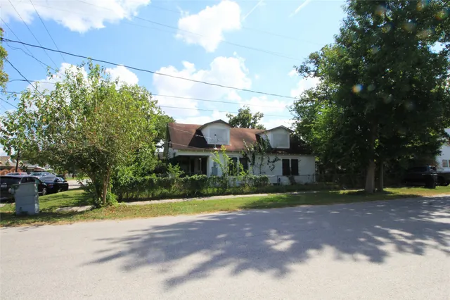 a view of a house with a yard and large trees