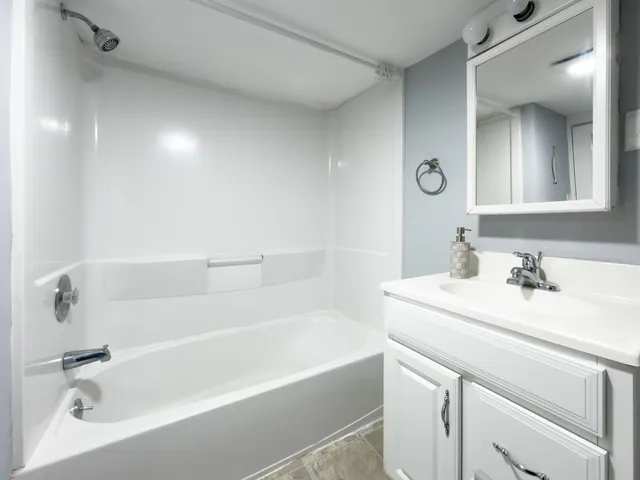 a white bath tub sitting next to a bathroom sink
