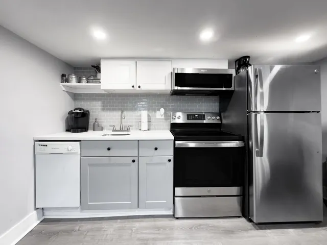 a kitchen with stainless steel appliances a refrigerator a stove and white cabinets