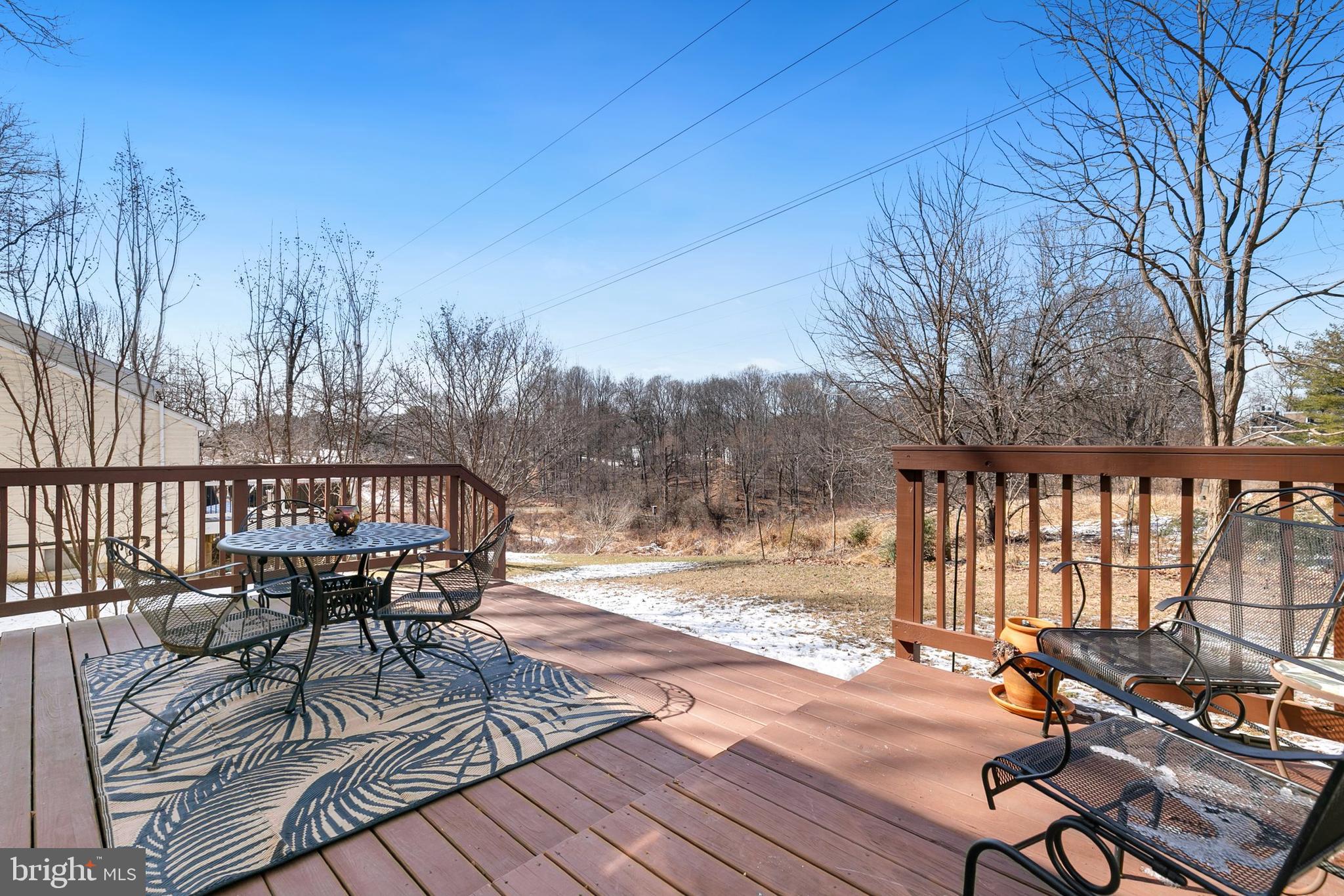 9348 Windbell Way Columbia, MD 21045 - Photo 32 of 37 a view of balcony with wooden floor outdoor seating and trees in the background