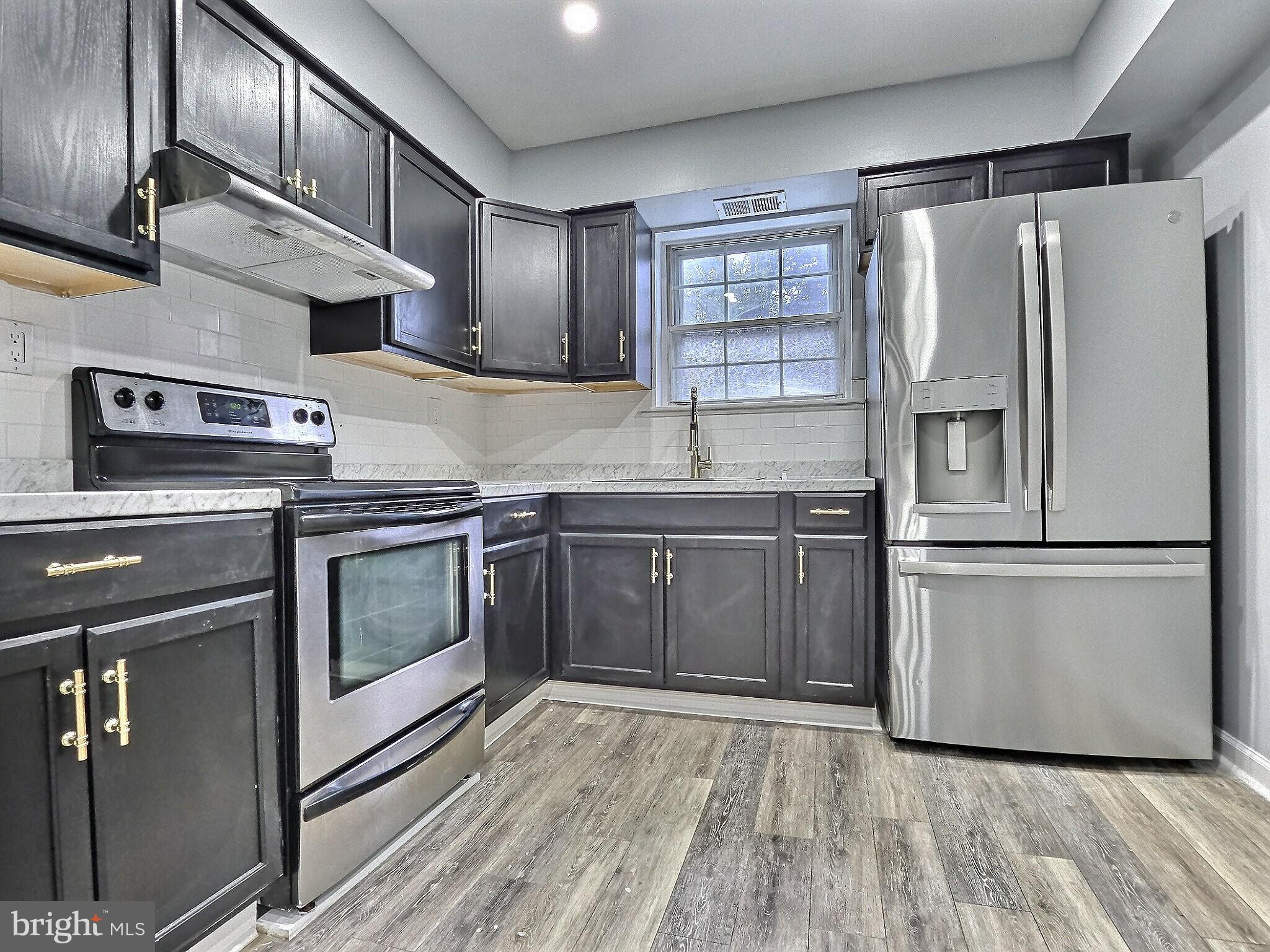 1213 Deer Run Reading, PA 19606 - Photo 17 of 42 a kitchen with stainless steel appliances granite countertop a refrigerator a stove and a sink with wooden floors