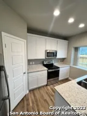 a kitchen with granite countertop a refrigerator and a stove top oven