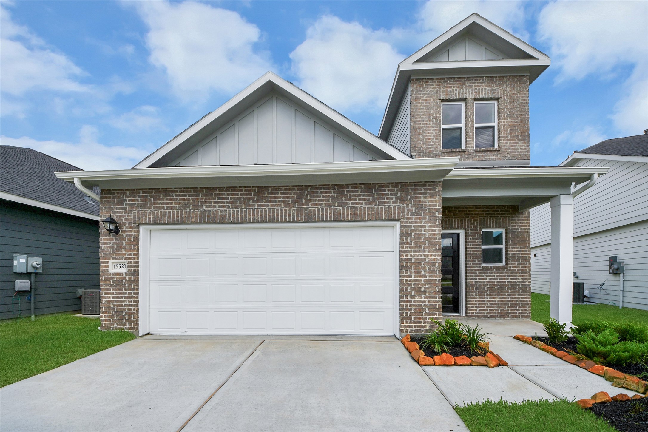 This charming home features a classic brick exterior with a modern design, a two-car garage, and a well-maintained front yard with simple landscaping. The architectural details include a gabled roof and a covered entrance, adding to its curb appeal.