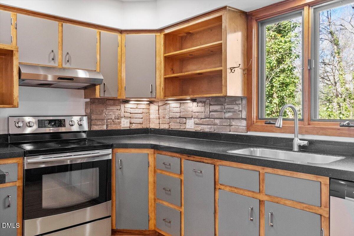 4805 Rembert Drive Raleigh, NC 27612 - Photo 9 of 45 a kitchen with granite countertop a sink cabinets stainless steel appliances and a window