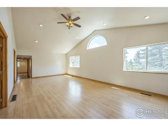an empty room with wooden floor fan and windows
