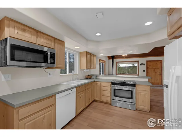 a kitchen with stainless steel appliances granite countertop a stove top oven a sink dishwasher a microwave oven and a refrigerator with wooden floor