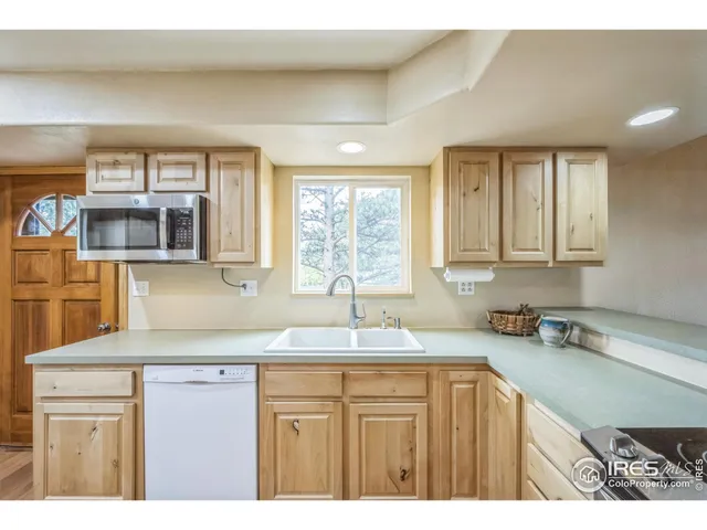 a kitchen with granite countertop a sink a window and cabinets