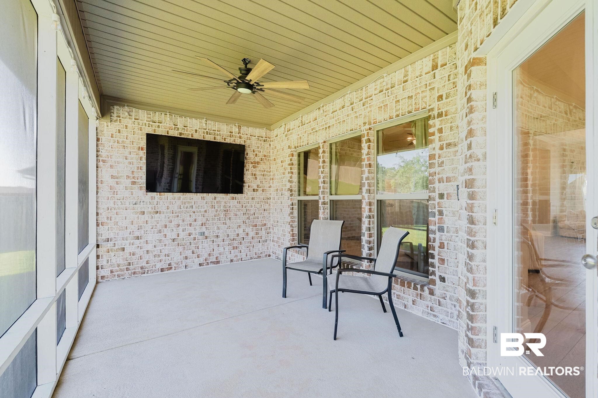 7872 Calverton Street Foley, AL 36535 - Photo 54 of 76 Screened outdoor living area featuring a brick accent wall, a mounted television, and a ceiling fan