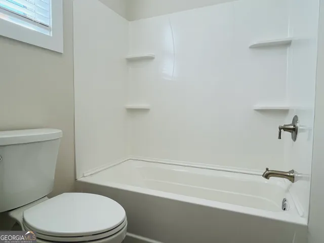 a white toilet and tub sitting next to a bathroom sink