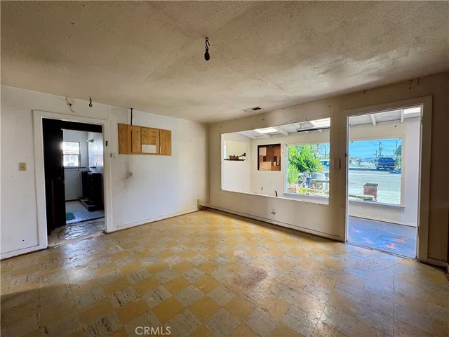 an empty room with kitchen view and windows