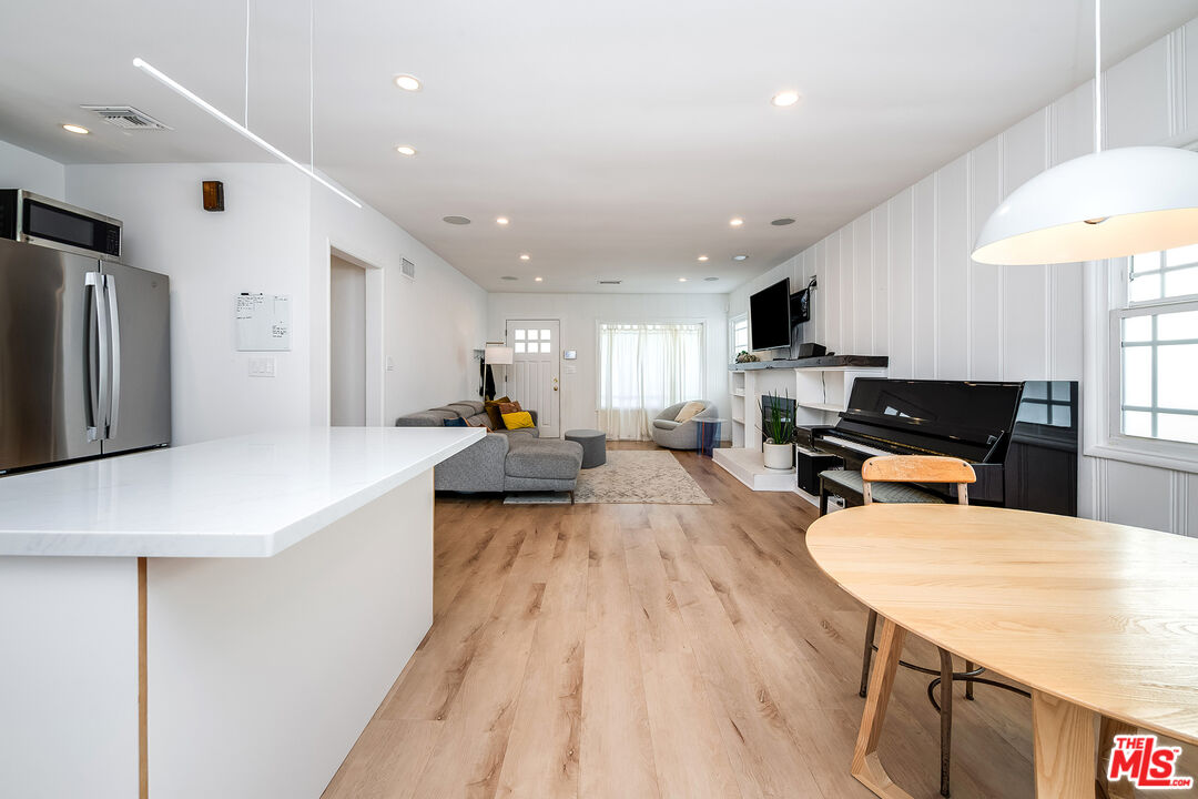 6660 Amigo Avenue Reseda, CA 91335 - Photo 19 of 25 a large kitchen with stainless steel appliances a refrigerator a sink dishwasher a stove and a dining table with wooden floor