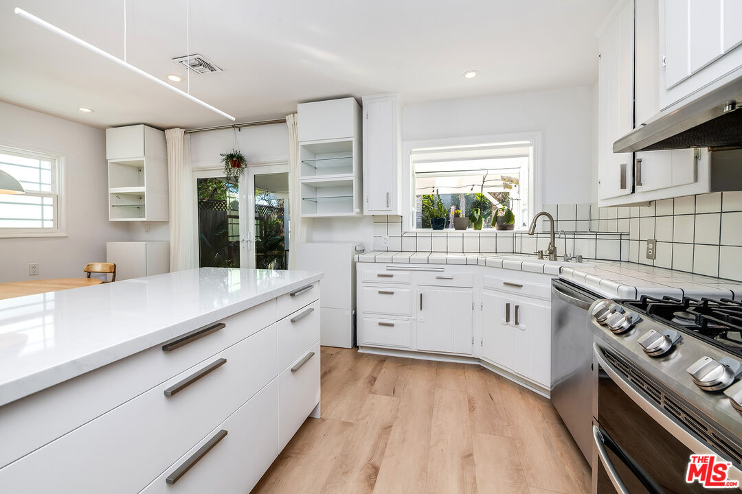 6660 Amigo Avenue Reseda, CA 91335 - Photo 8 of 25 a kitchen with stainless steel appliances sink a stove and white cabinets