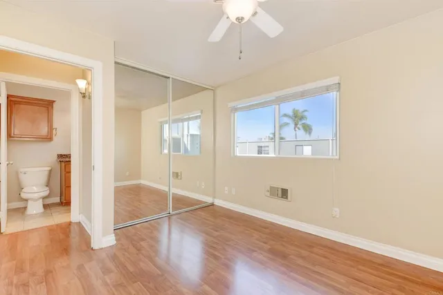 a view of an empty room with wooden floor and a bathroom
