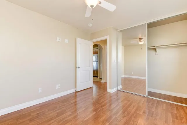 an empty room with wooden floor and a ceiling fan