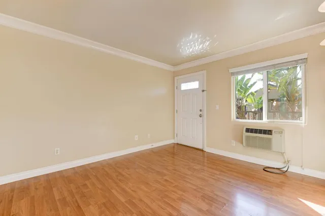 a view of an empty room with a window and wooden floor