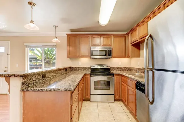 a kitchen with stainless steel appliances granite countertop a refrigerator a stove a sink and a microwave