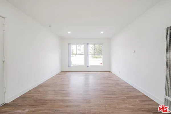 a view of an empty room with wooden floor and window