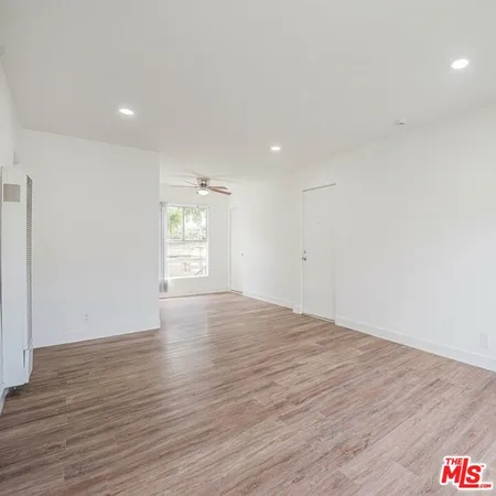 a view of empty room with wooden floor and fan