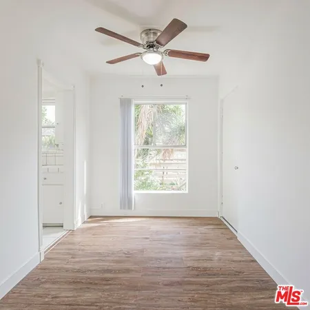 an empty room with wooden floor chandelier fan and windows