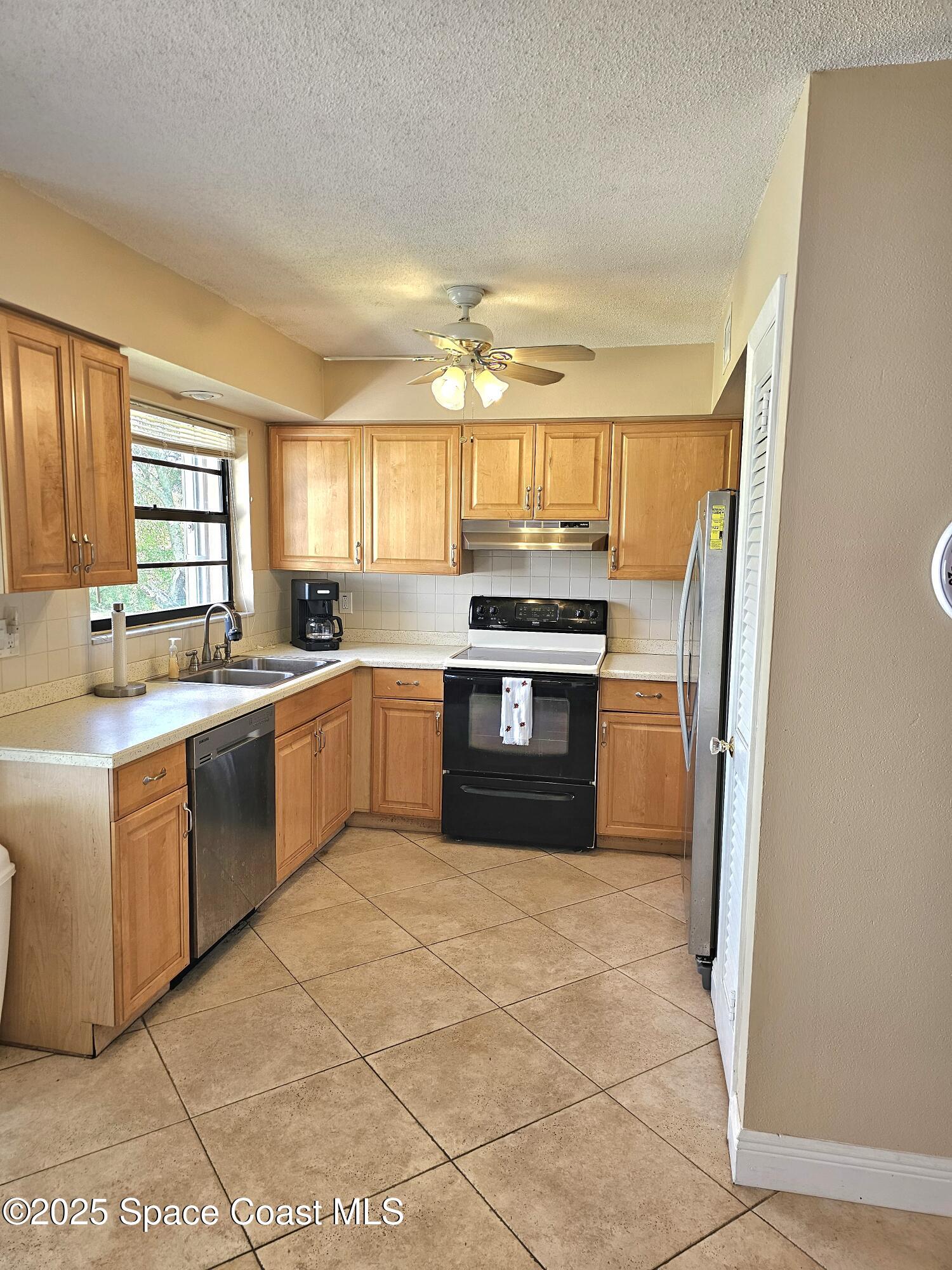 898 Hampton Drive Northeast Palm Bay, FL 32905 - Photo 3 of 20 a kitchen with stainless steel appliances granite countertop a stove a sink and a refrigerator
