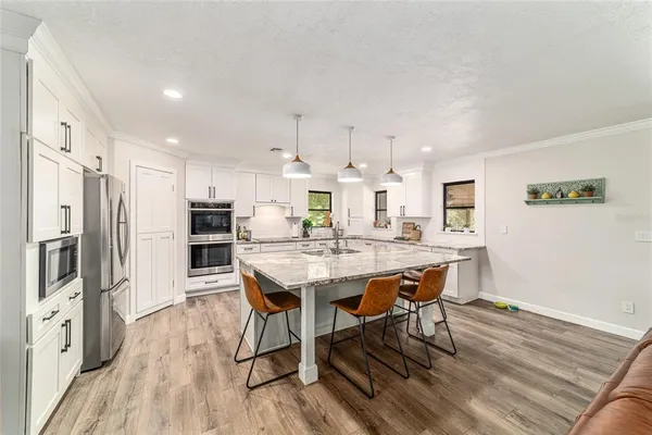 a kitchen with stainless steel appliances a dining table chairs stove refrigerator and wooden floor