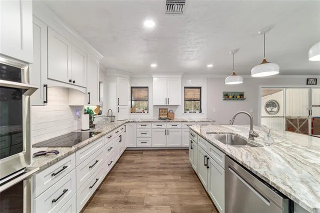 a large kitchen with granite countertop a large counter top appliances and cabinets