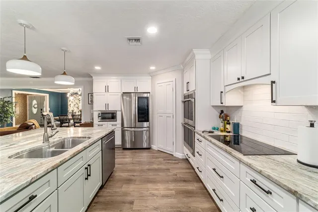 a large kitchen with stainless steel appliances lots of counter space and a sink