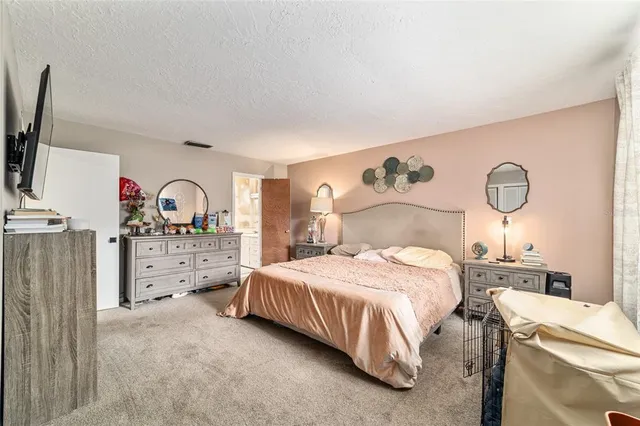 a bedroom with a bed and a flat tv screen on dresser