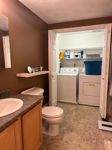 a bathroom with a granite countertop toilet sink and mirror