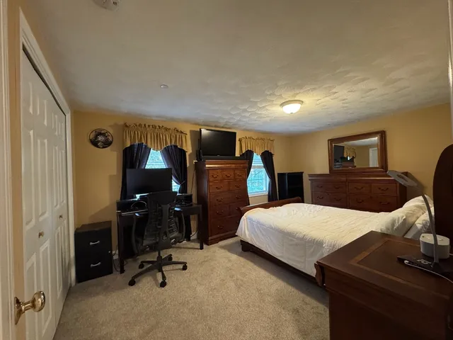 a bedroom with bed and a flat tv screen on dresser