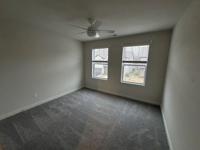 an empty room with windows and fan