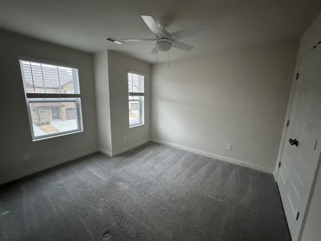 an empty room with windows and ceiling fan