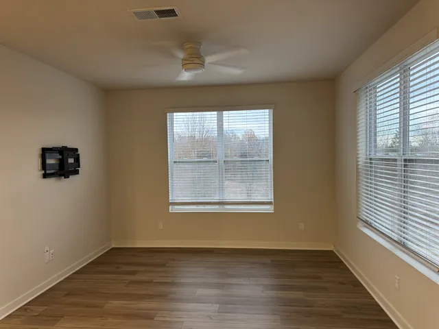 an empty room with wooden floor and windows