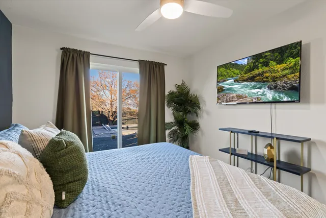 a bedroom with a large bed a chandelier and a flat tv screen
