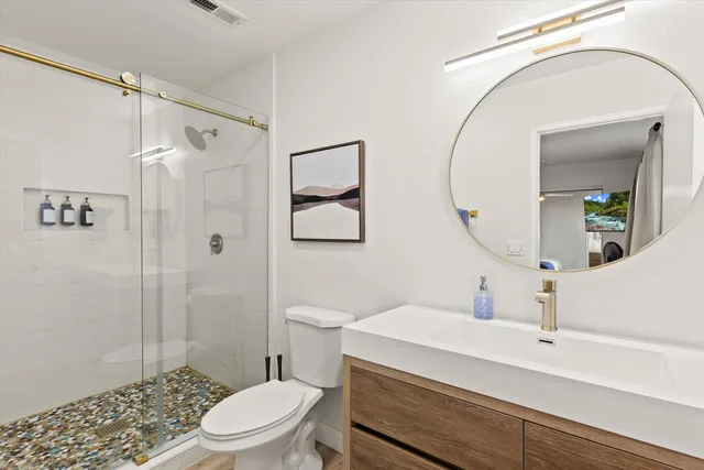 a bathroom with a sink a toilet a mirror and shower