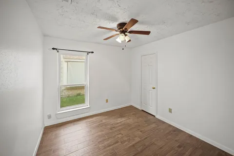 an empty room with a window and a ceiling fan