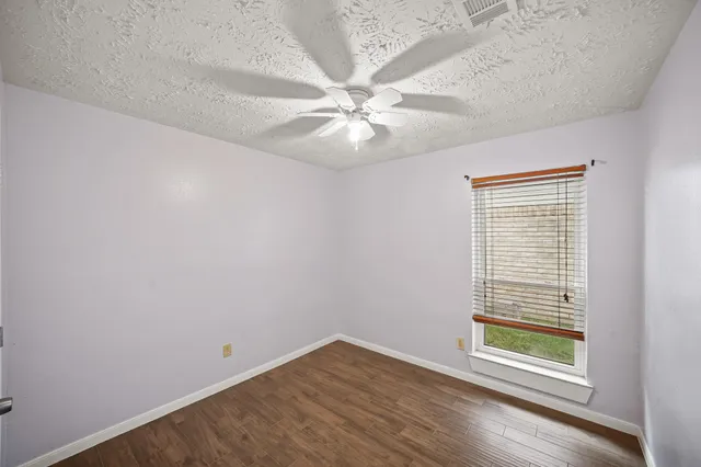 an empty room with windows and fan