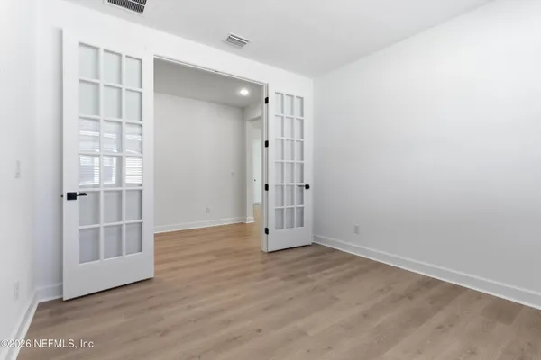 an empty room with wooden floor and windows